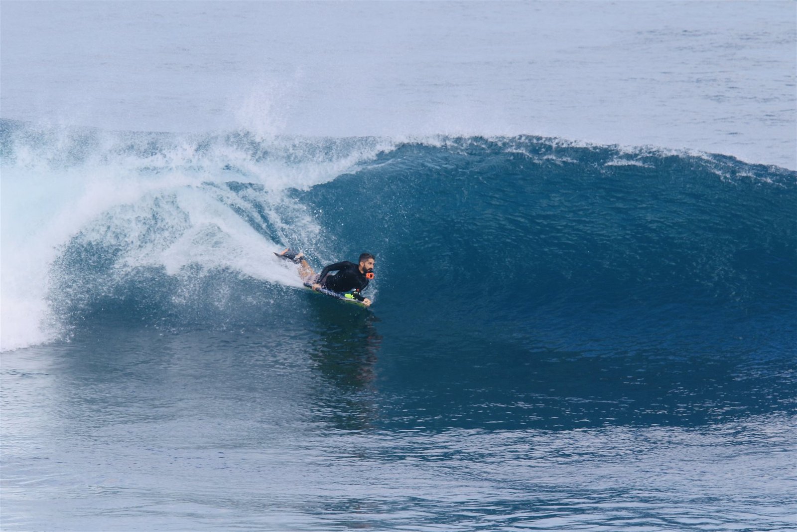 Bodyboarder riding the face of a blue wave